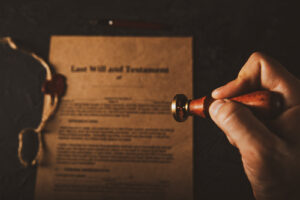 Image of a Last Will & Testament document and a hand with a stamp. 