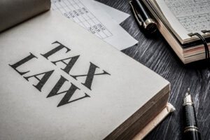 Keep Calm and Prepare Your Taxes Properly. An image of a tax law book and accounting forms.