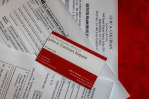 Will You Find Yourself in a New Tax Bracket in 2023? Image of the John A. Cochran, Esq red and white business card and tax forms.