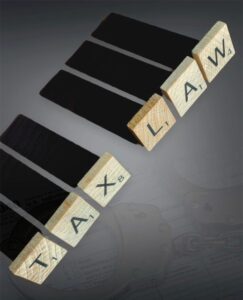 Tax Evasion-What Not to Do. Image of Scrabble pieces spelling Tax Law with a gray background and handcuffs.
